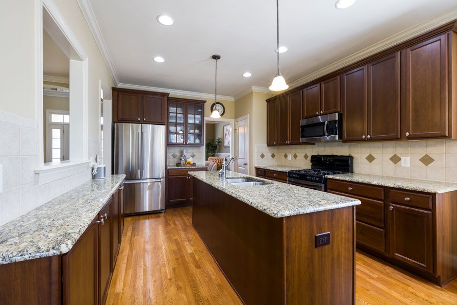 Spacious modern kitchen featuring granite countertops and wooden cabinetry.