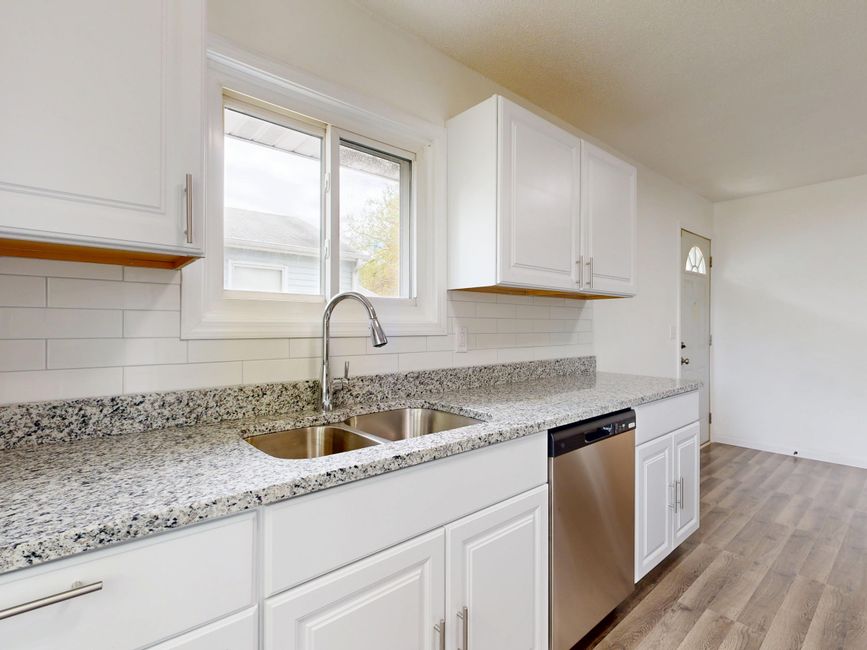 Bright modern kitchen with granite countertops and stainless steel appliances.
